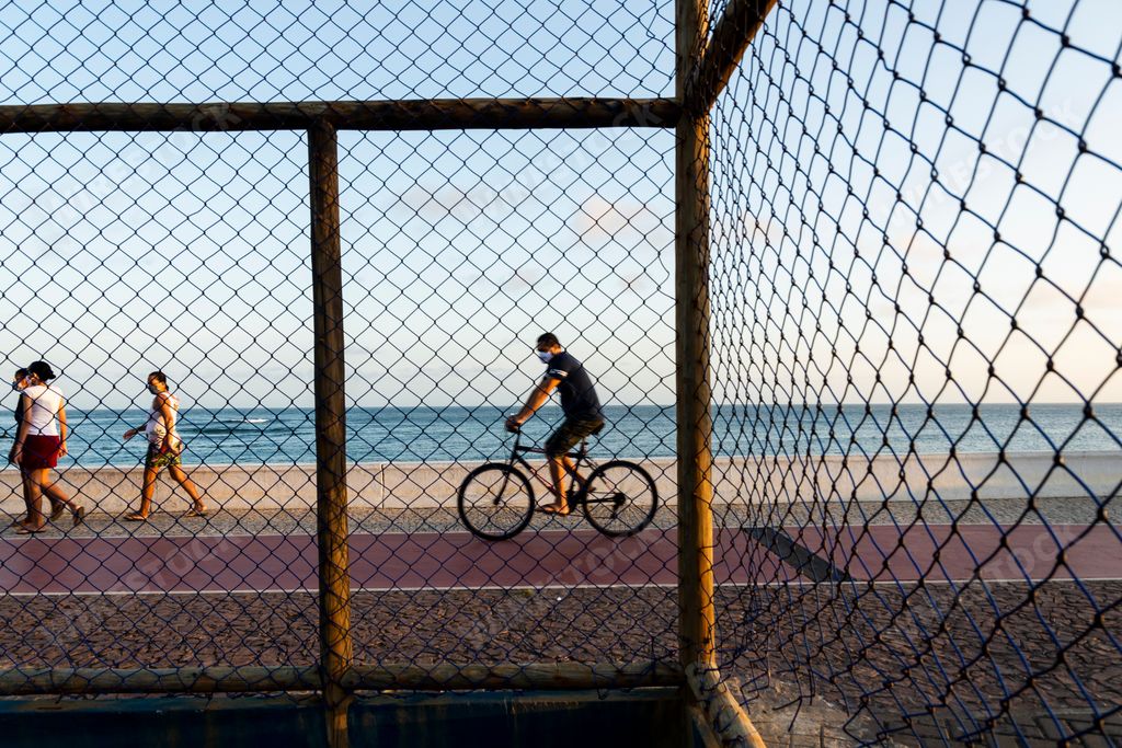 People and a cyclist on Paciencia beach in Rio Vermelho neighborhood in ...