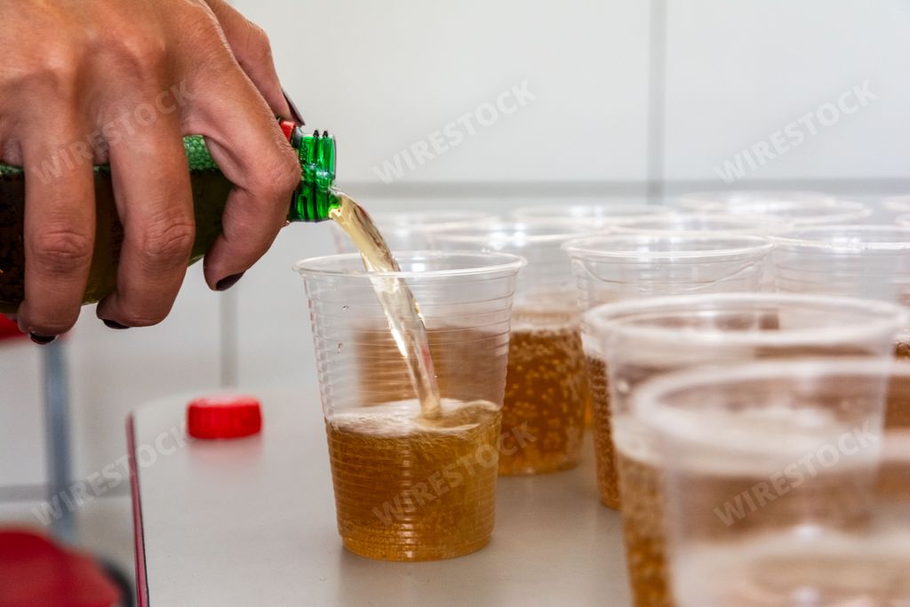 A hand pouring a soda into a plastic cup