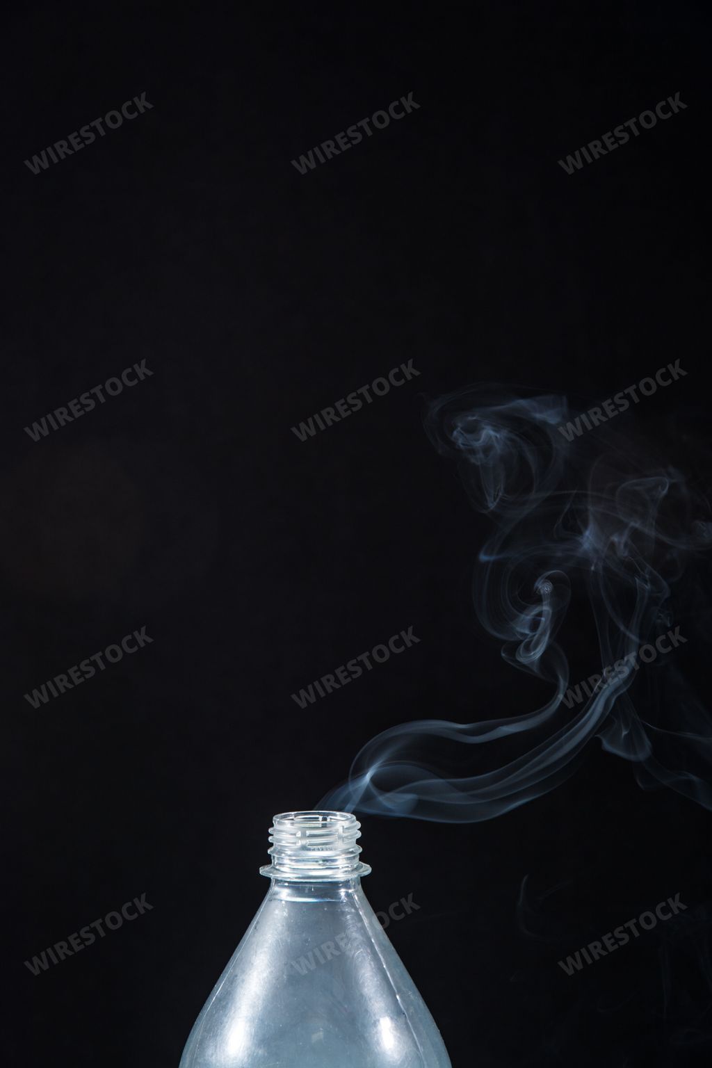 Smoke coming out of a plastic bottle against a black background. Background for Halloween. Texture fog. Design element. The concept of aromatherapy.