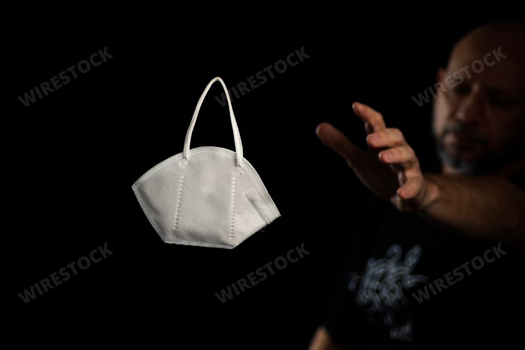A Portrait of a protective mask against covid-19 against a black background and a man