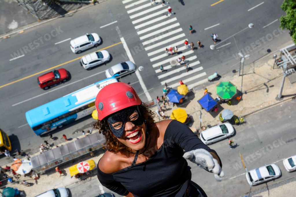 A closeup of a woman walking down a tall Rappel building above the streets