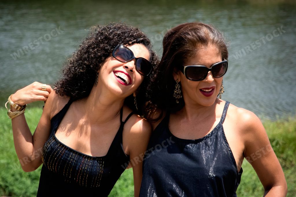 A portrait of two young sister females wearing sunglasses against a river in  Salvador, Bahia, Brazil