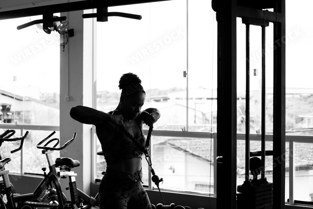A black female athlete performing face pulls in a gym setting