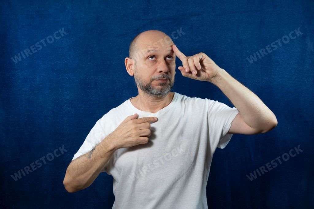 A thoughtful bearded bald man posing against blue background
