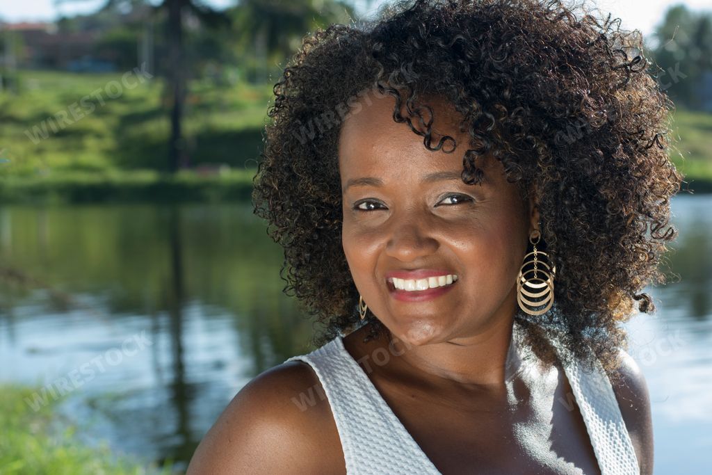 A smiling  Portuguese black woman looking at the camera against the river of Salvador, Bahia, Brazil