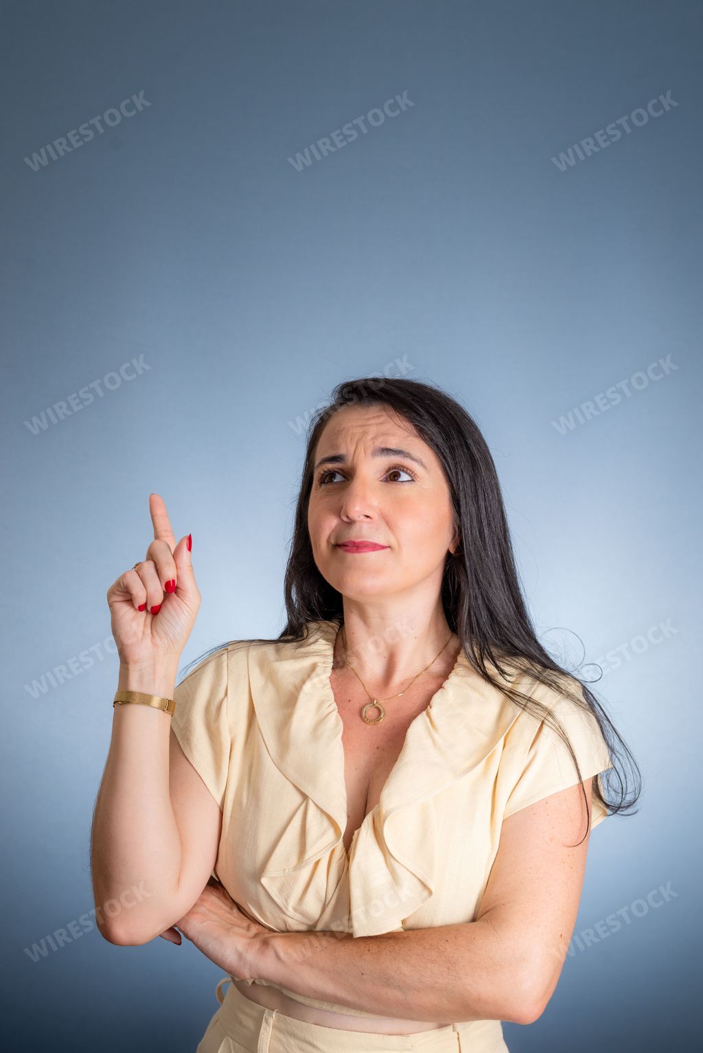 A young female is standing outdoors pointing towards the sky, her finger outstretched in the direction of a bright red object