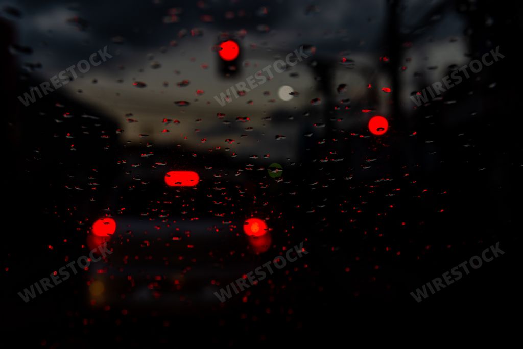 Colored lights blur through the car window, wet with raindrops. Heavy and slow traffic.