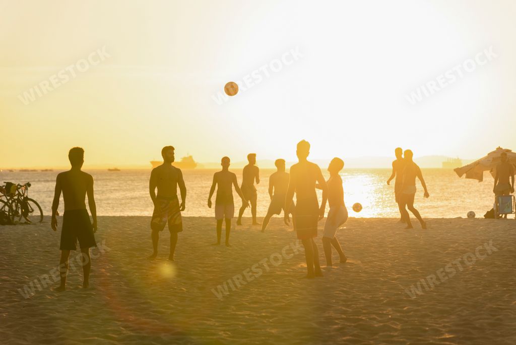 Young people playing beach soccer during sunset at Ribeira beach in Salvador, Bahia, Brazil.