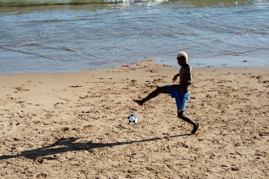 A young man playing sand football on the beach in summer in Salvador, Bahia, Brazil