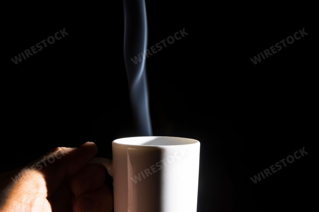 A male hand holding a white cup with smoke against a black background