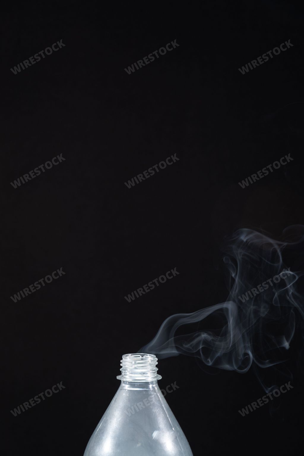 The smoke coming out of a plastic bottle on black background -  aromatherapy concept