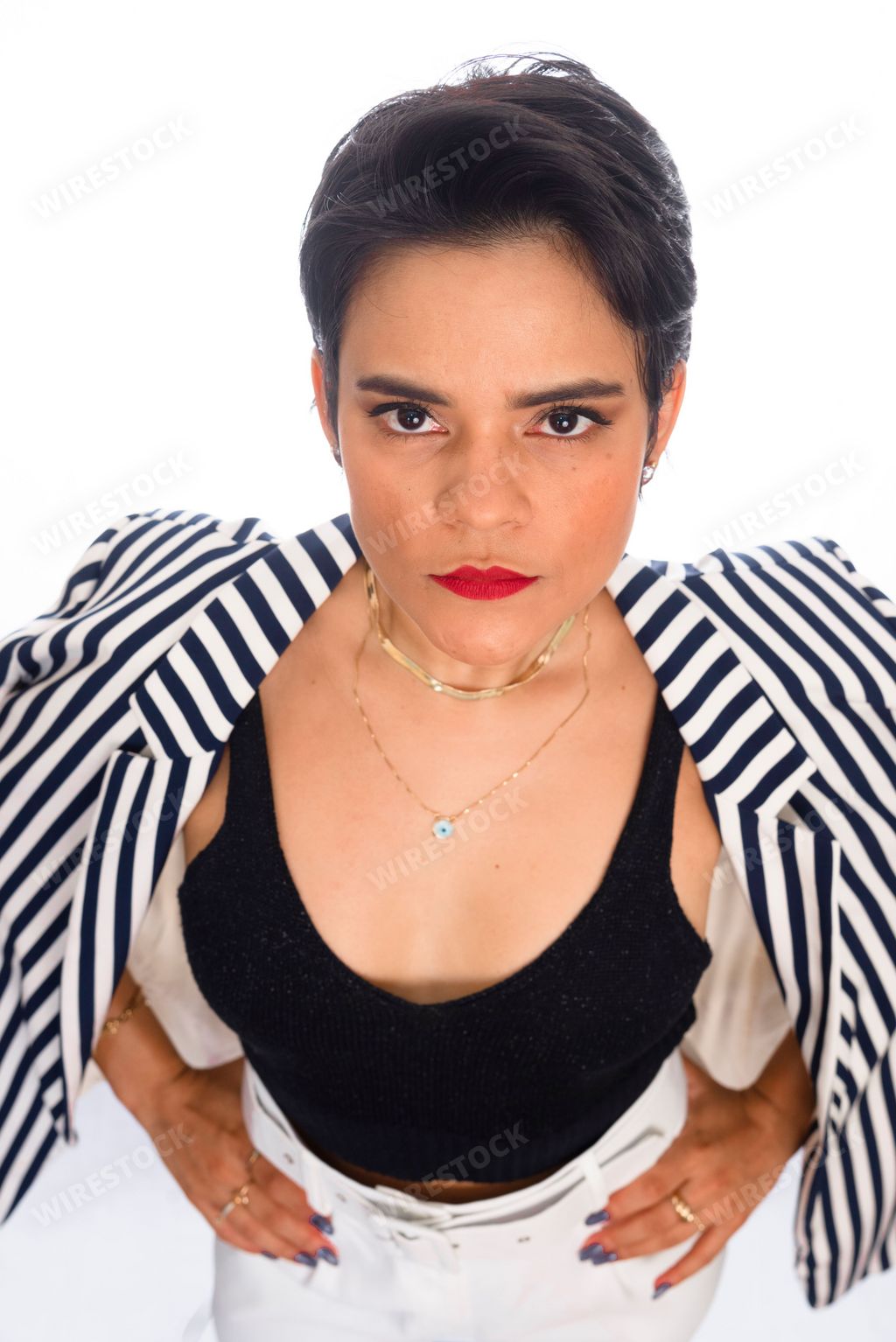 A vertical portrait of a businesswoman in a formal outfit standing in front of a white background