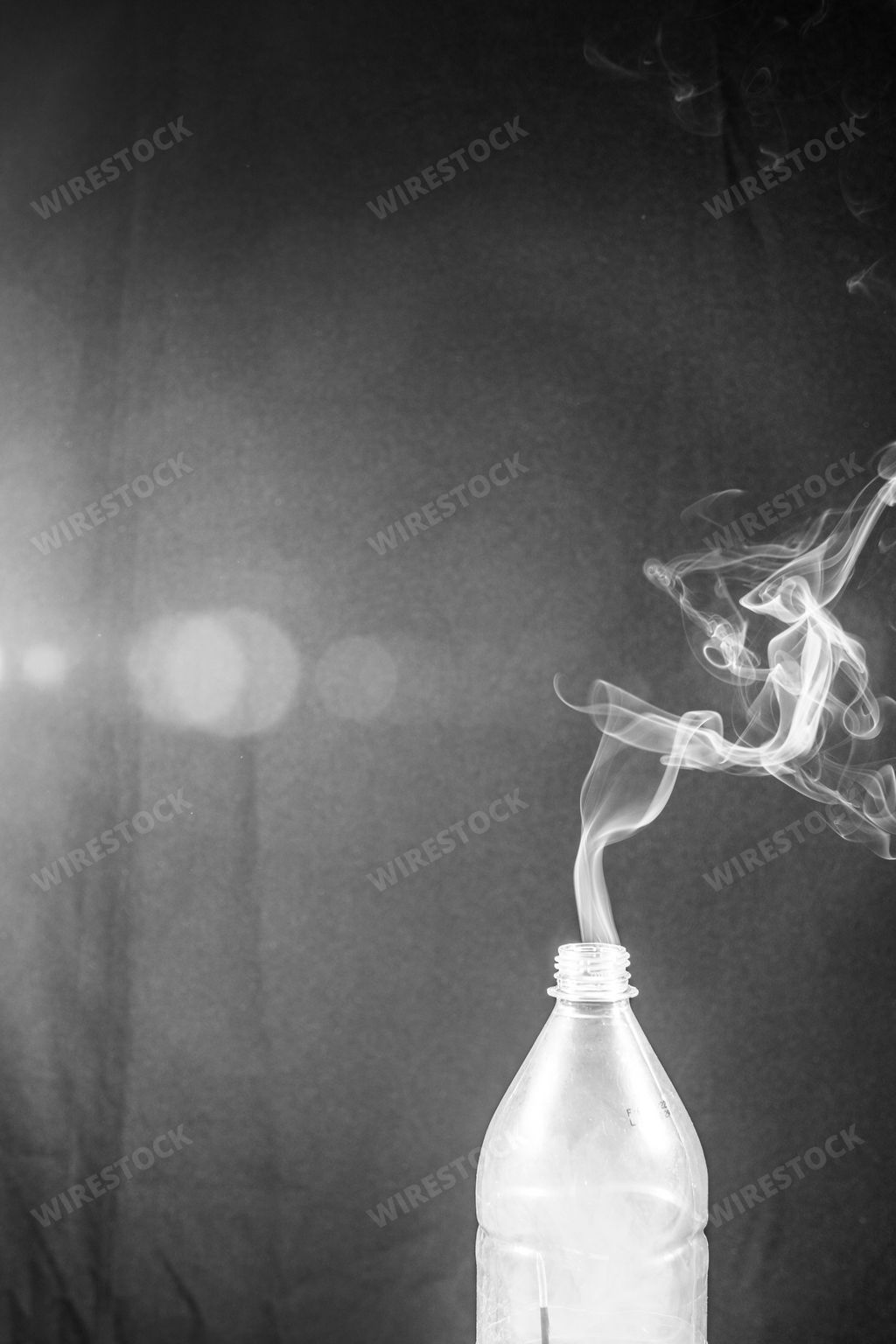The smoke coming out of a plastic bottle on black background with flare -  aromatherapy concept