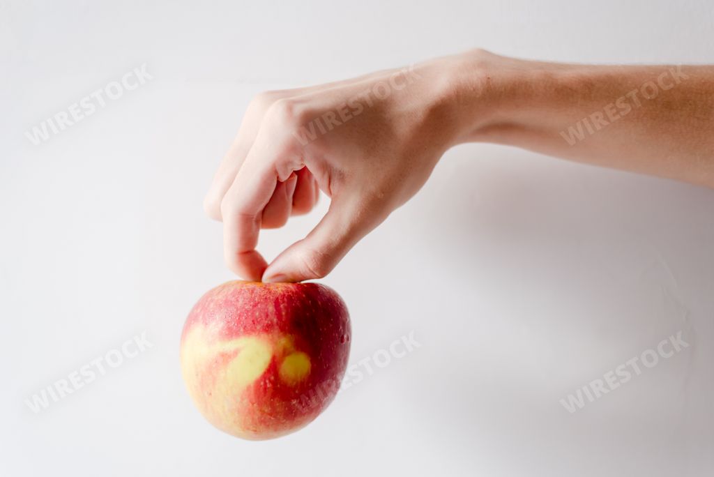 A hand holding an apple against white background. Salvador, Bahia, Brazil.