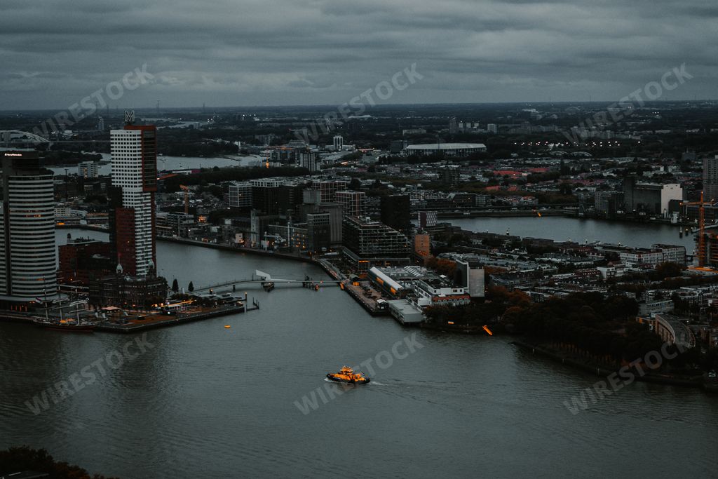 A bird's eye view of a boat in a river and skyscrapers in Rotterdam, the Netherlands
