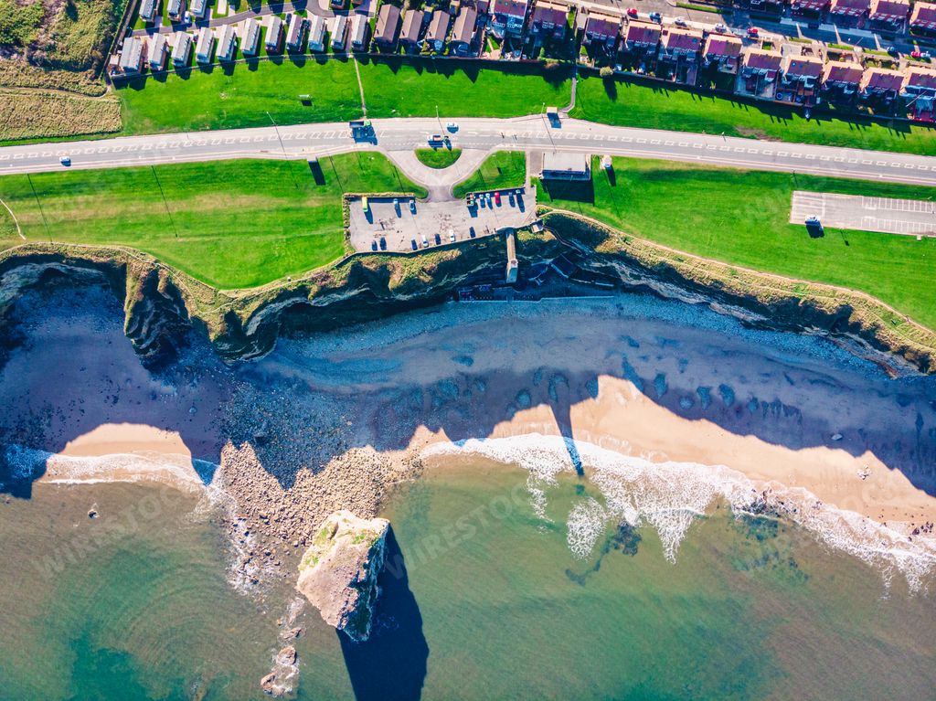A drone shot of a beautiful shore with a green lawn in South Shields, UK