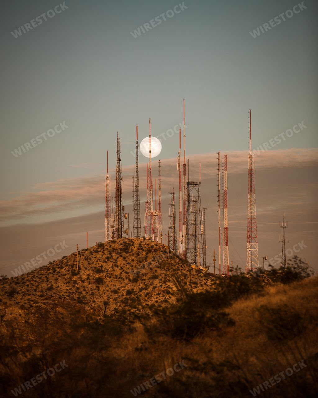 A vertical shot of a full moon rises over the radio towers on South Mountain in Phoenix, Arizona