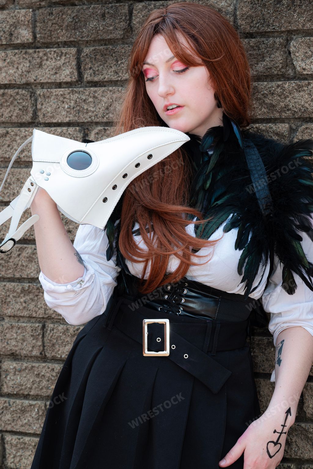 A female cosplayer dressed as a plague doctor with a white mask.