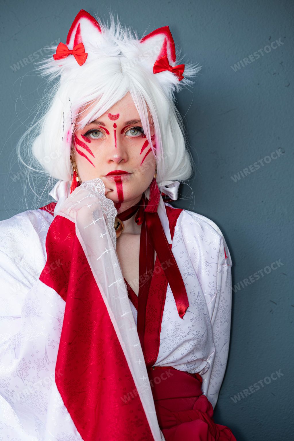 A cosplayer dressed in a Japanese white and red cat priestess costume