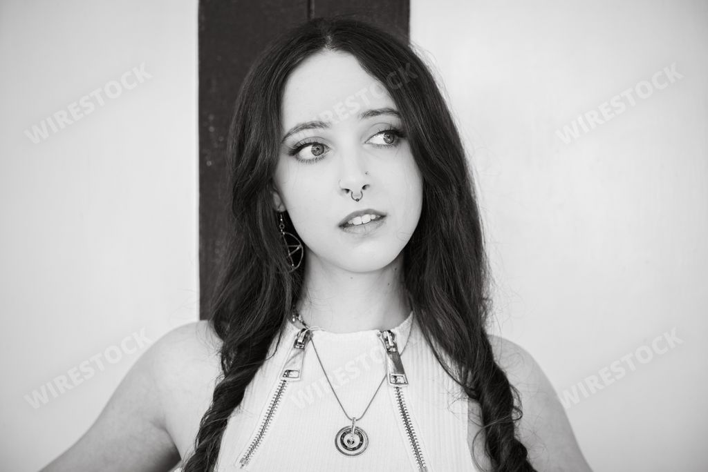 A grayscale shot of a goth girl in an urban setting