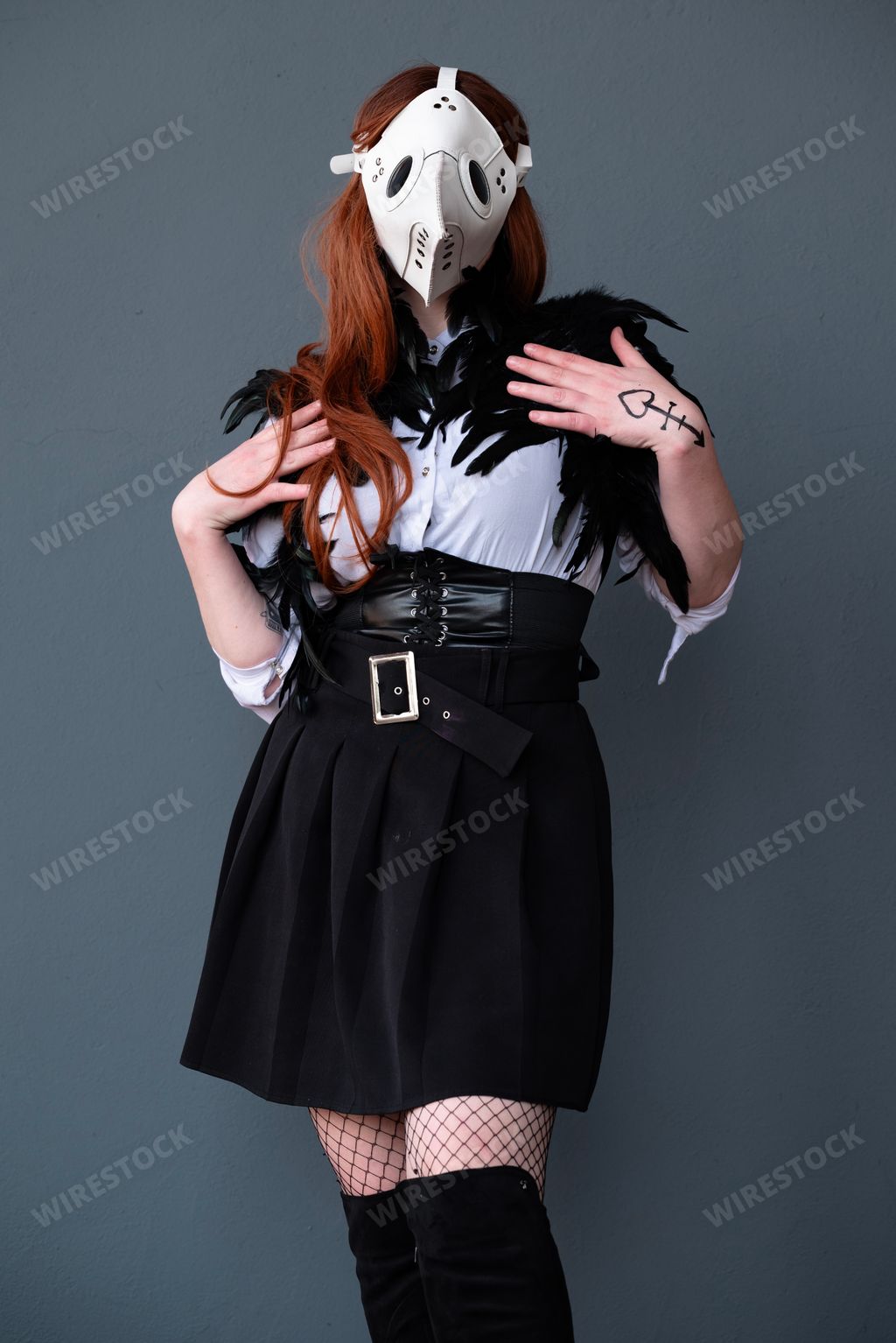 A female cosplayer dressed as a plague doctor with a white mask.