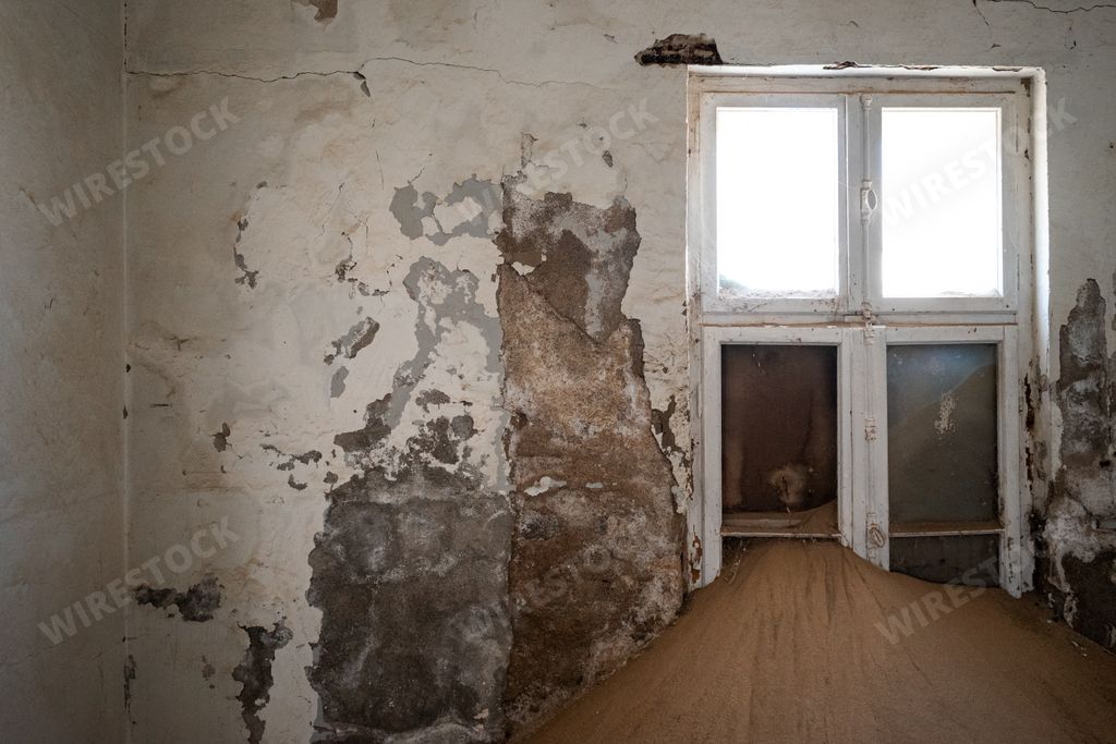 A room featuring a distressed wooden floor and peeling walls in an old desert town