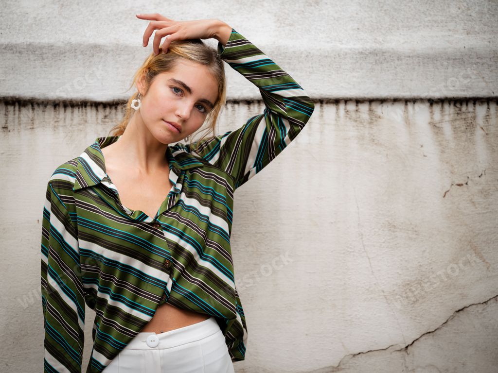 An attractive blonde Caucasian girl with blue eyes posing in soft summer clothes