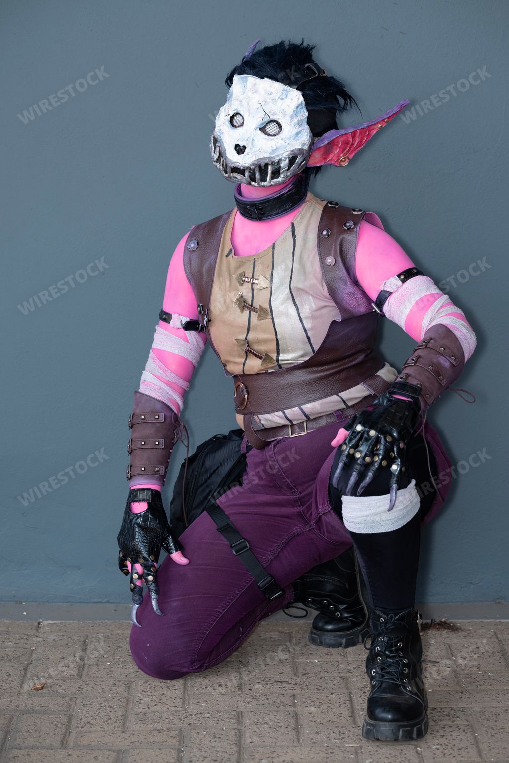 A female cosplayer dressed as a pink monster with a skull mask