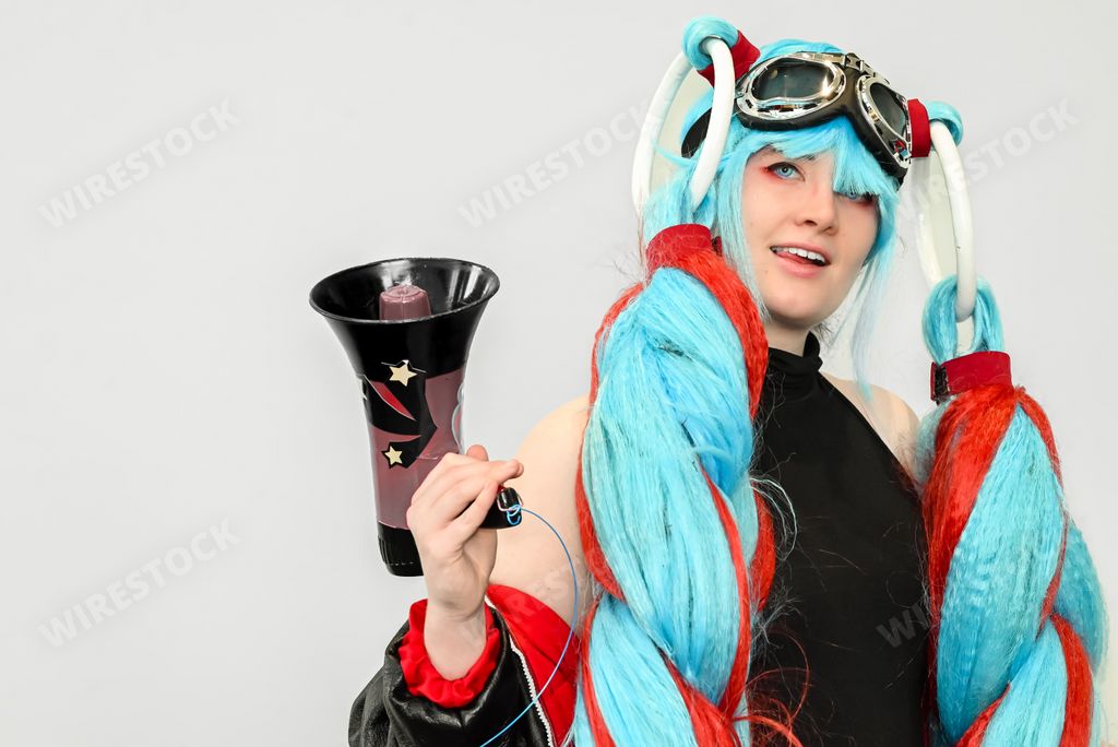 A female cosplayer dressed as an anime character with blue hair and a megaphone