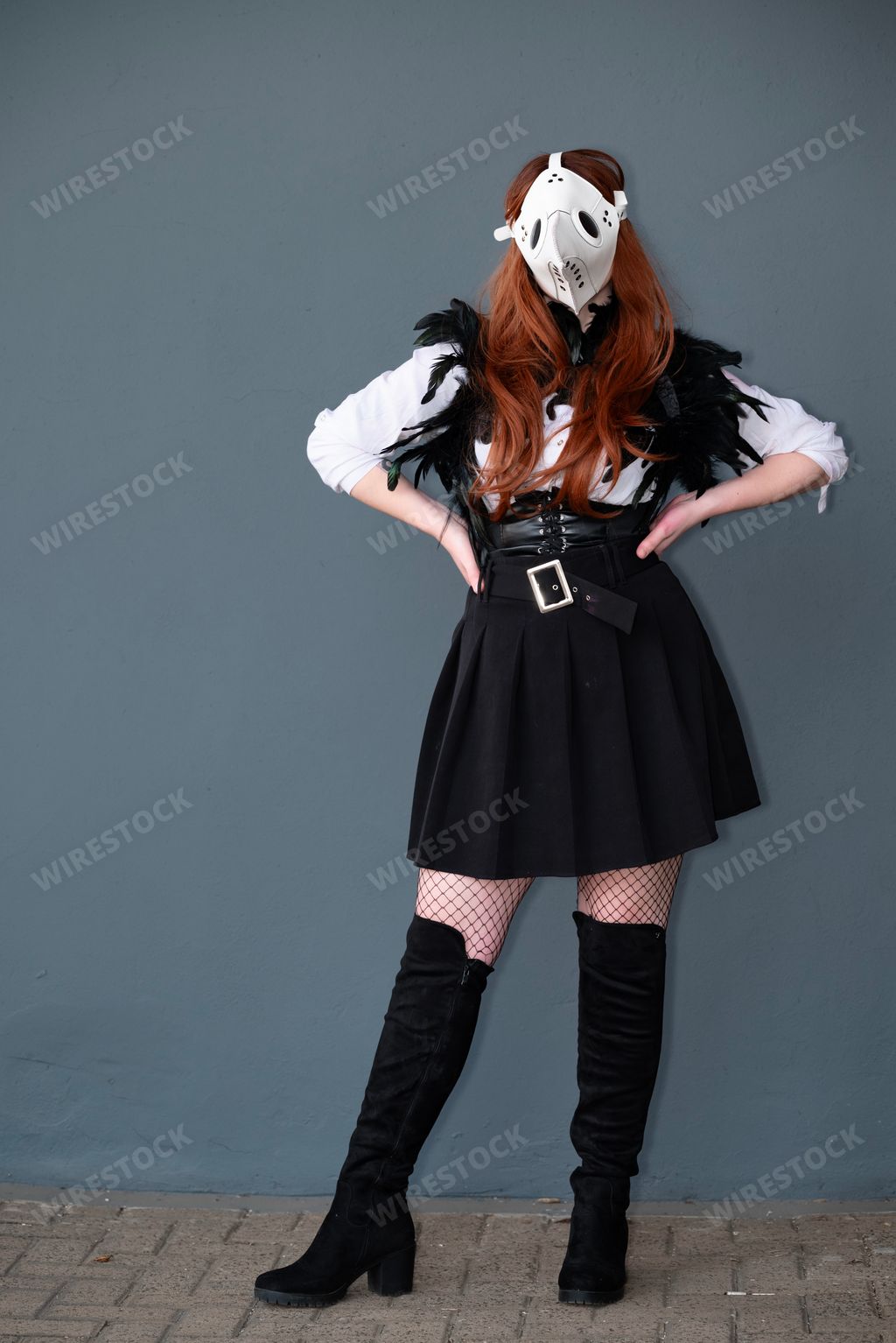 A female cosplayer dressed as a plague doctor with a white mask.