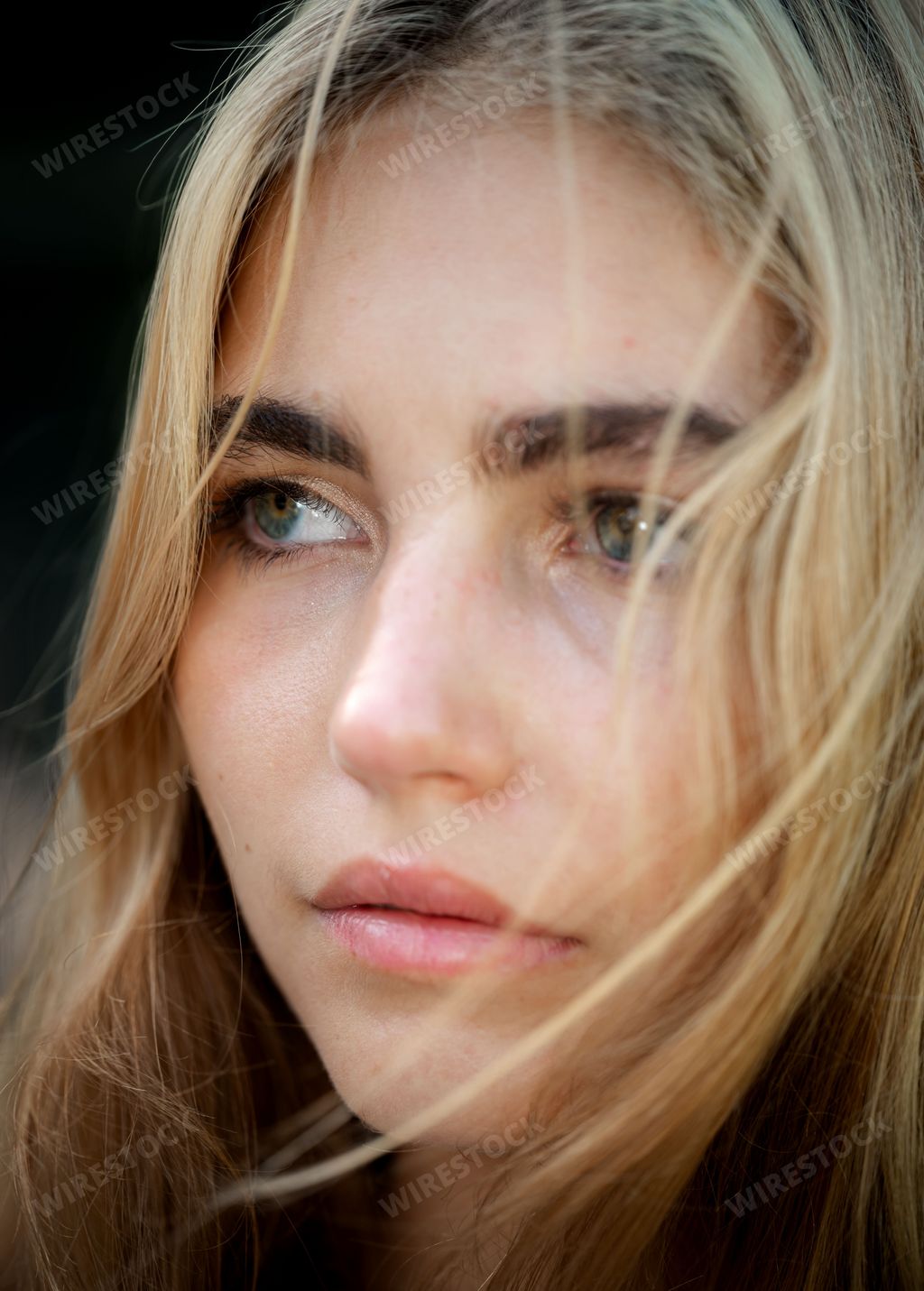 Closeup of a young blonde woman looking out into the distance with a thoughtful expression on her face
