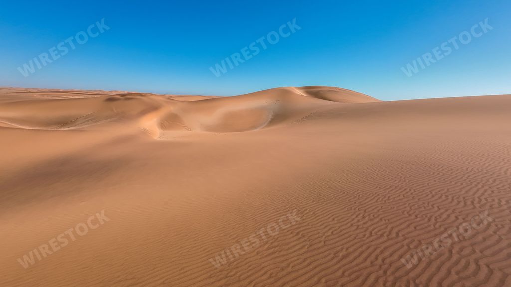 A serene desert landscape with sand dunes and clear blue sky in Namibia, Africa