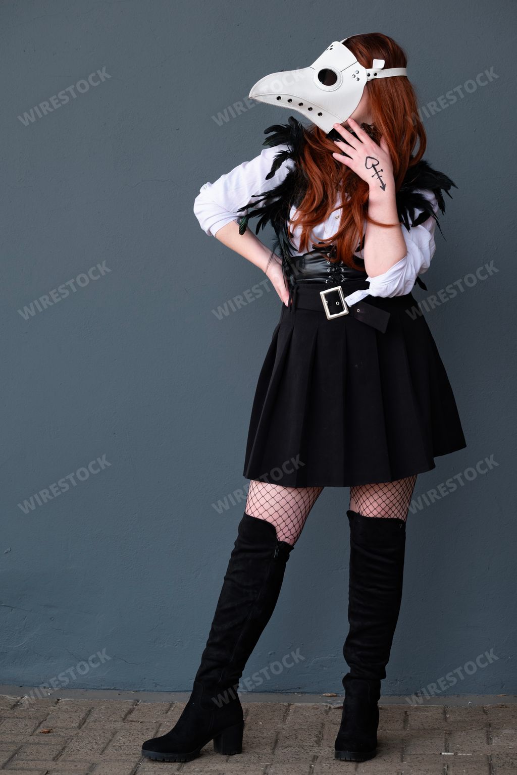 A female cosplayer dressed as a plague doctor with a white mask.