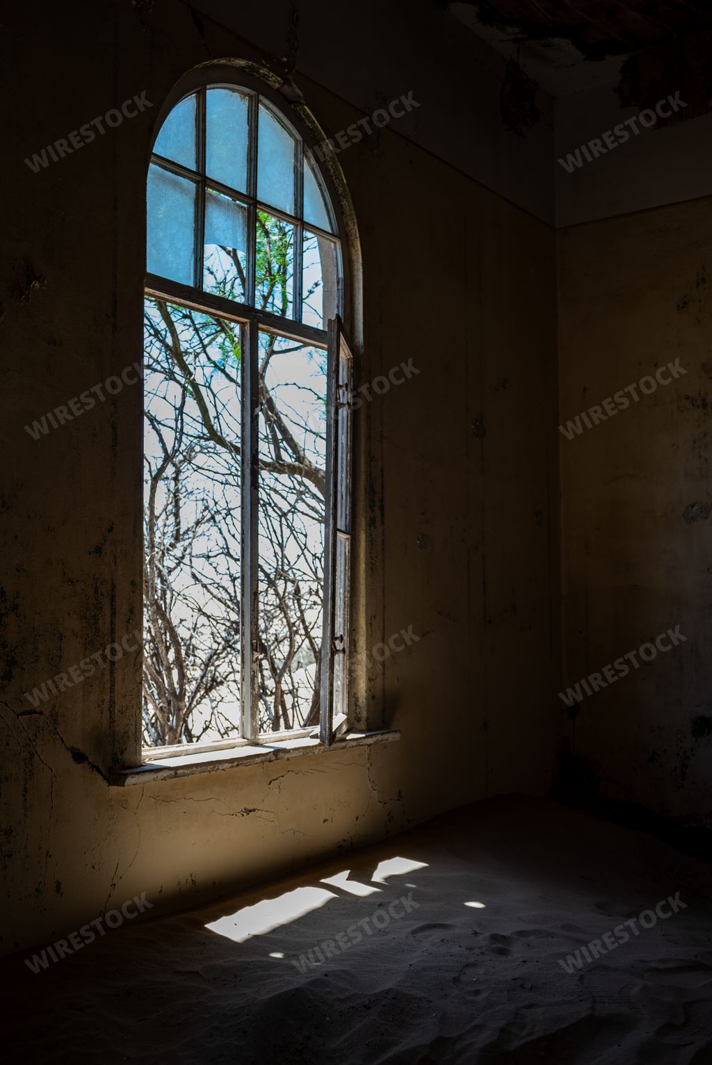 An abandoned interior space with an illuminated window in an old desert town
