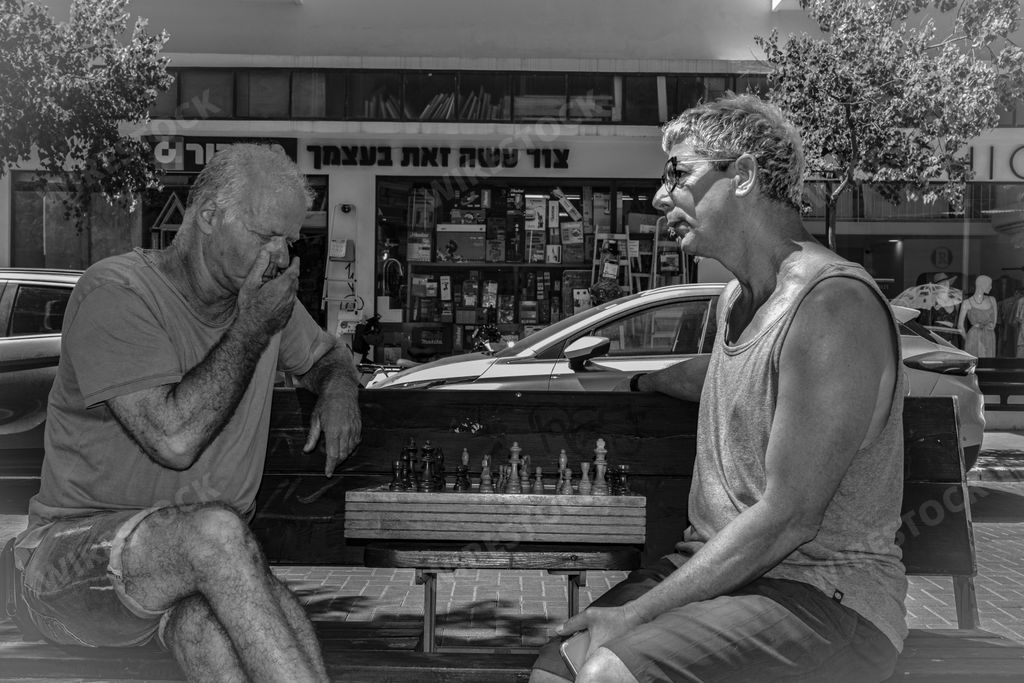 The two adult male friends enjoying a conversation in front of a shop.
