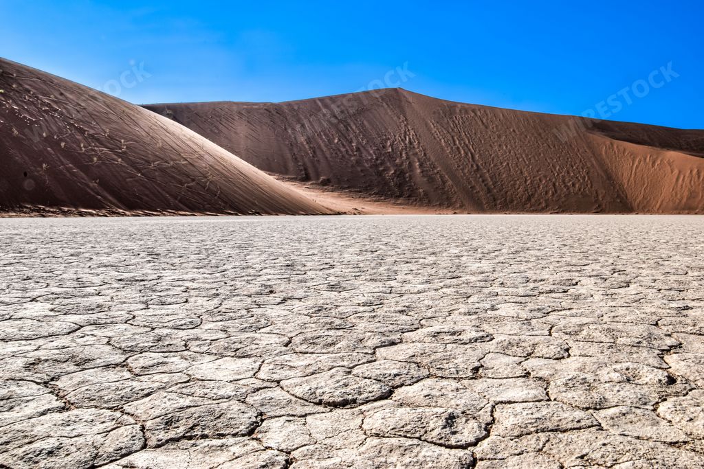 A vast, sun-drenched desert landscape under a clear, blue sky, Sossusvlei, Namibia