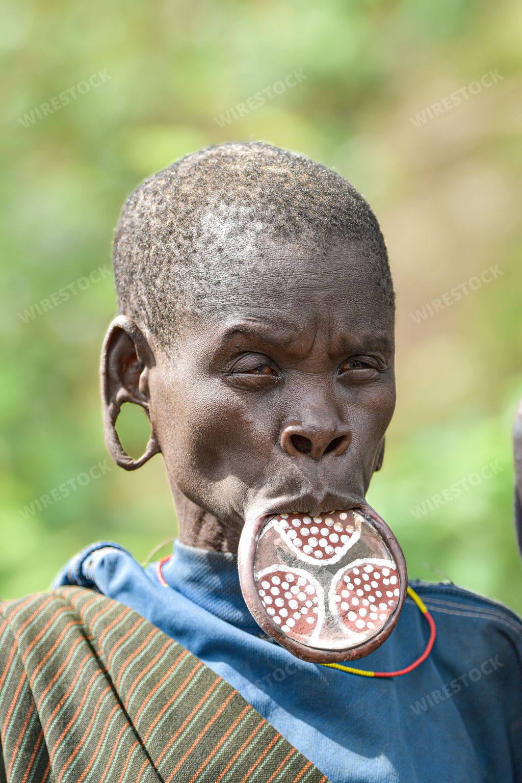 A vertical shot of an African male with traditional jewelry and body modifications from an Ethipoian tribe
