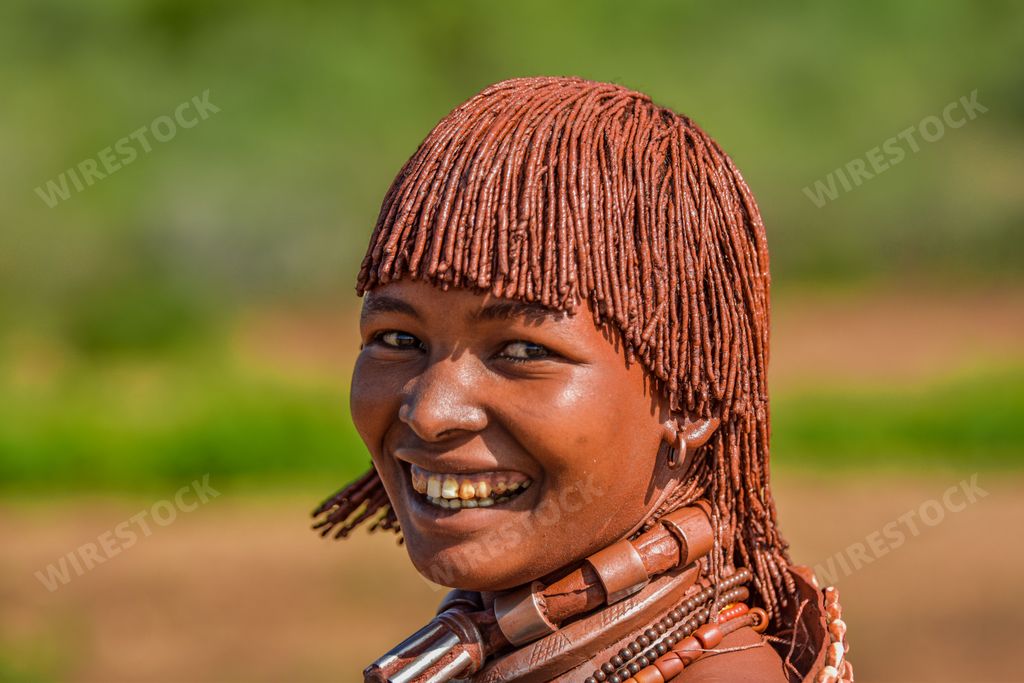 A happy young African female in a traditional headdress and body paint from the Ethiopian Hamer tribe
