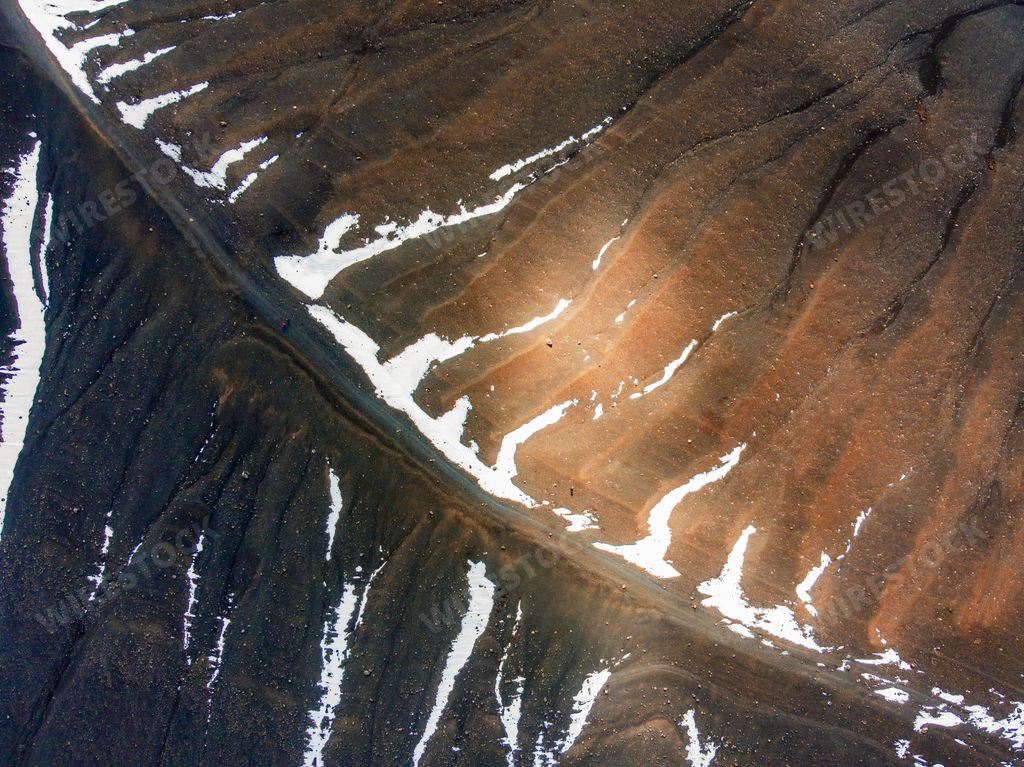 An aerial view of a mountain slope with melting snow