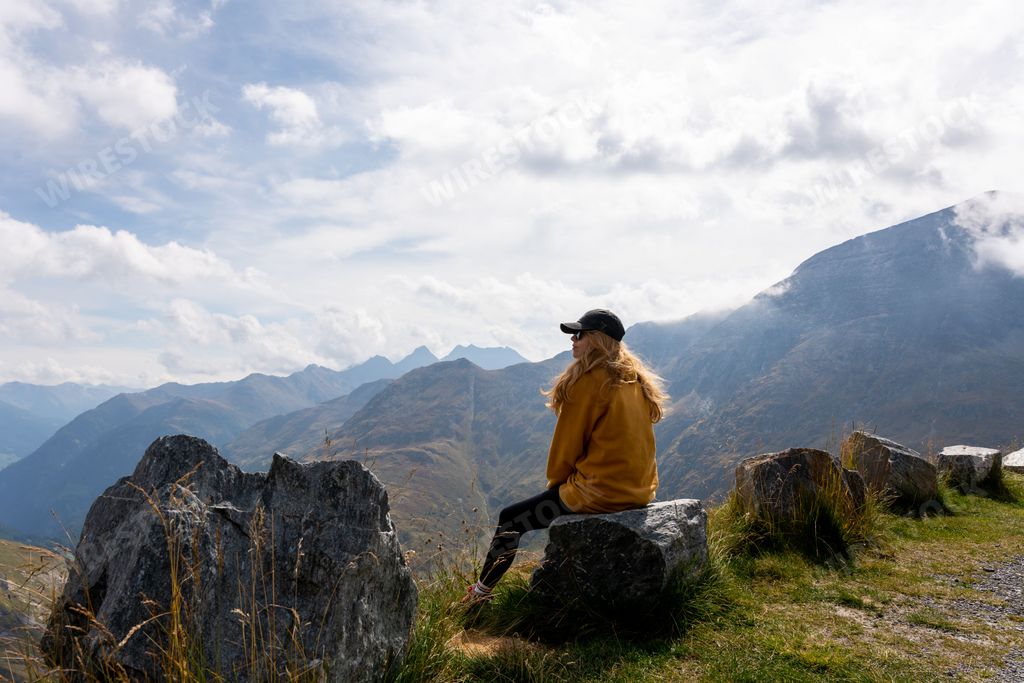 A back view of a blonde female hiker enjoying the view of mountains near Grossglockner, Austria