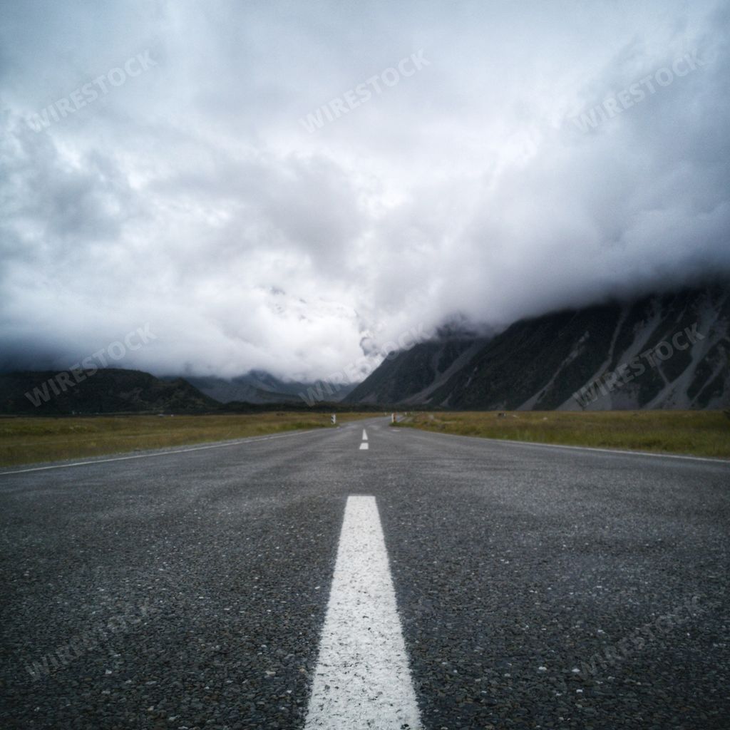 A low angle shot of an empty highway under the cloudy sky