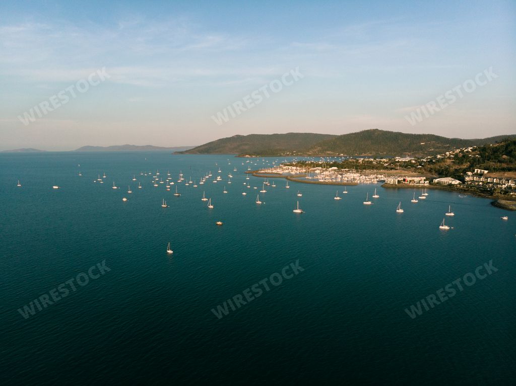 A high angle shot of boats on sailing on the sea under a blue sky