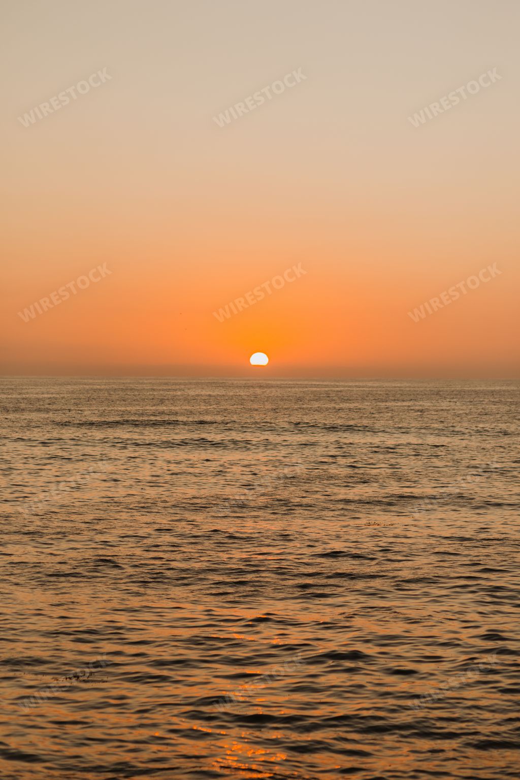 A vertical image of a beautiful orange sunset at the ocean
