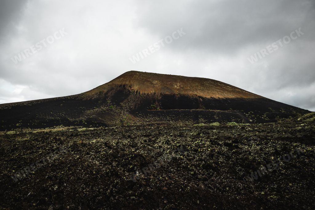 Volcano and lava field in Timanfaya National Park, cloudy sky, Lanzarote.