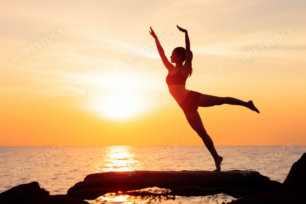 An AI generated illustration of A young female stands atop a large rock formation overlooking a tranquil ocean at sunset