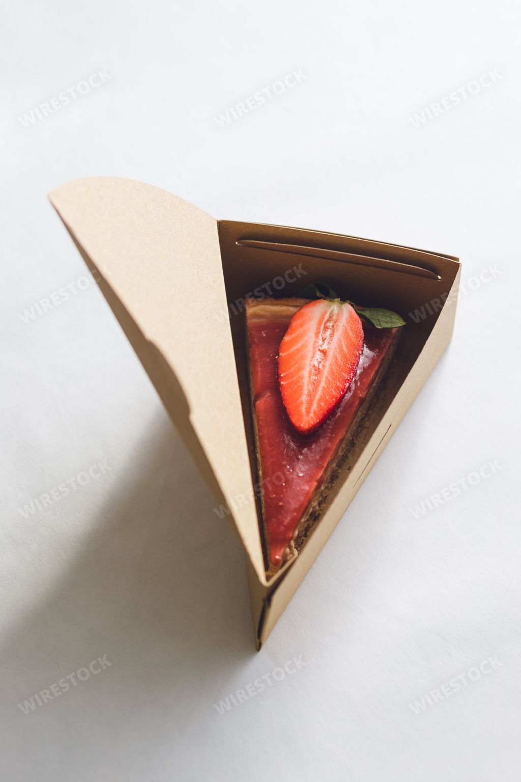 A top view of a Strawberry cheesecake in a triangular cake box