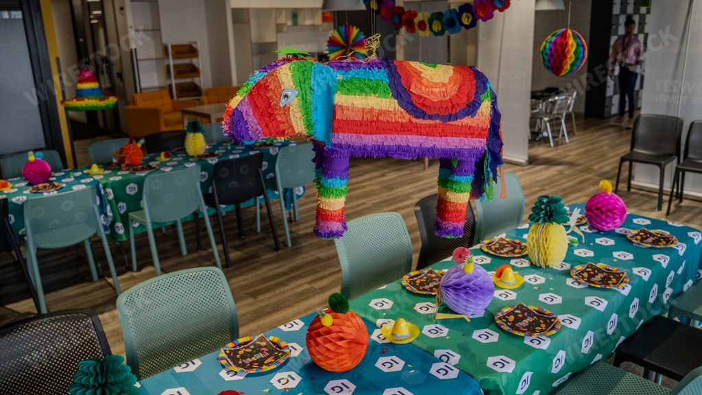 A colorful, traditional Mexican pinata shaped like an animal, resting above a tabletop