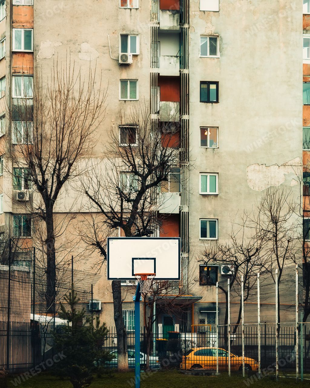 A vertical shot of a basketball court in between grey blocks of flats in Berceni, Bucharest, Romania