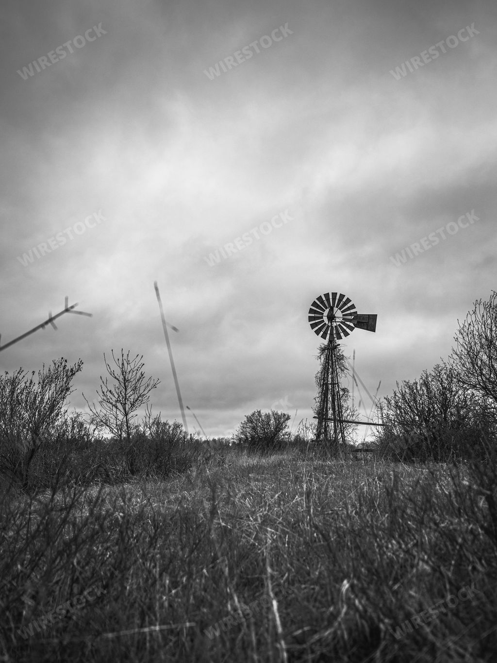 Black and white image of an abandoned windmill with ominous dark clouds in the sky above