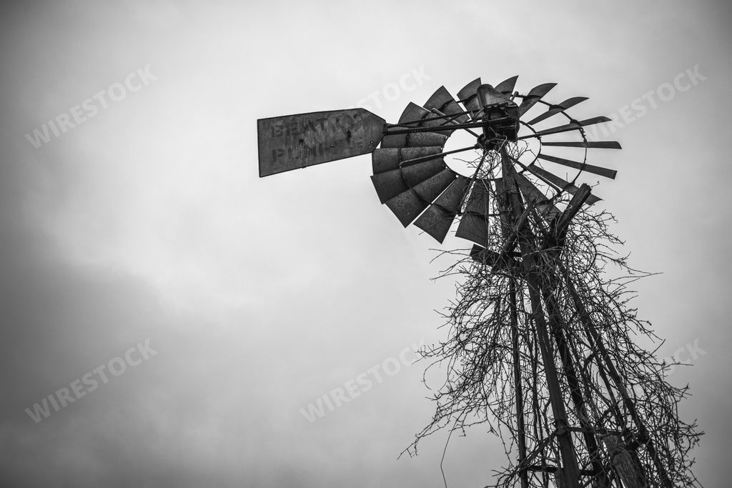 Black and white image of an abandoned windmill with ominous dark clouds in the sky above